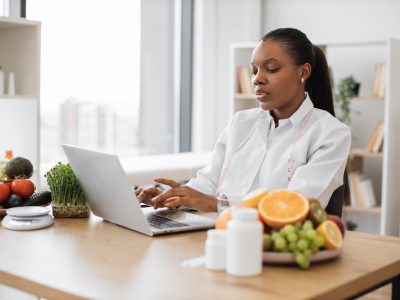 Food expert typing on laptop in consulting room of clinic