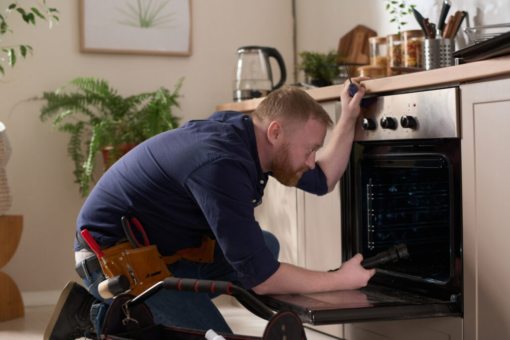 Worker repairing oven at home
